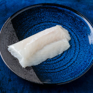 Raw white fish fillet on a blue-speckled ceramic plate