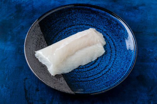 Raw white fish fillet on a blue-speckled ceramic plate