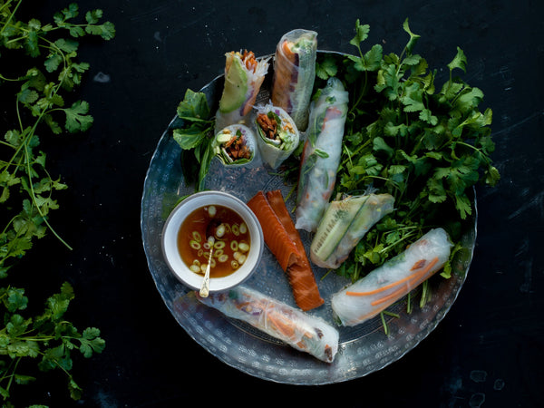 Spring rolls with salmon, fresh herbs, and dipping sauce on a decorative plate