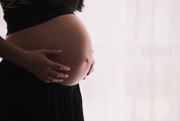 Pregnant woman holding her belly in soft light.