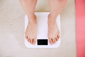 Bare feet standing on a white digital bathroom scale with black display