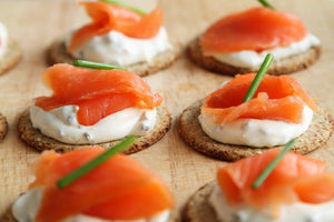 Round whole-grain cracker with cream cheese, smoked salmon slice and chive garnish