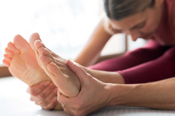 Person stretching and holding their feet, focusing on foot health or pain relief.