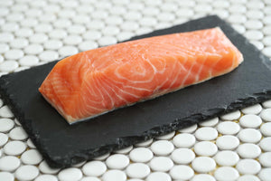 raw salmon fillet on black slate plate