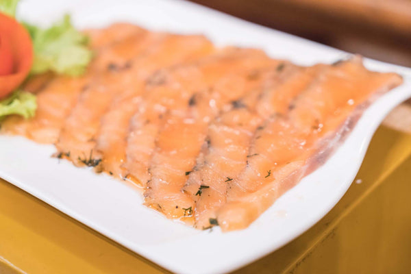 Thinly sliced smoked salmon with dill on a white serving platter