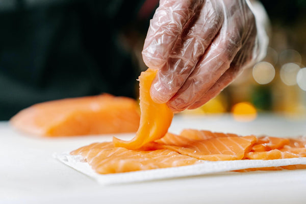 a person holding a slice of raw fish