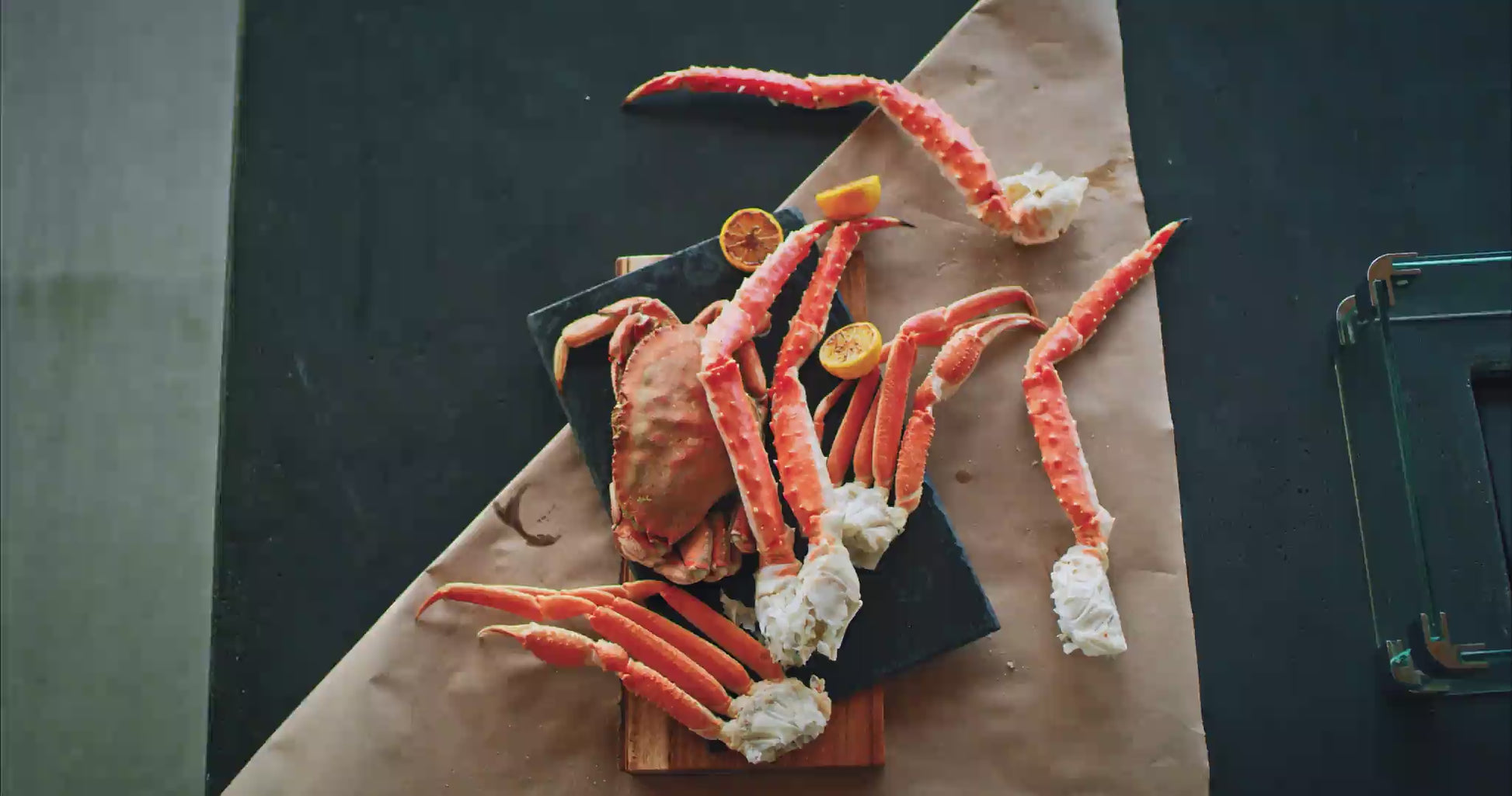 Cooked king crab legs with lemon halves and a dish of melted butter on parchment